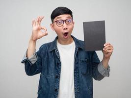 Positive asian man wear glasses jeans shirt show the book and hand ok isolated photo