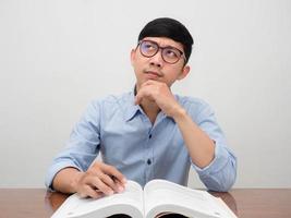 Asian man wear glasses sit working at the desk gesture thinking photo