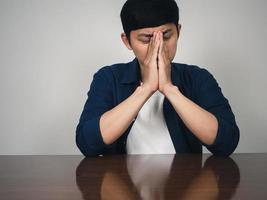 el hombre asiático sentado a la mesa se siente deprimido y triste por la vida foto