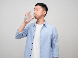 joven asiático camisa azul agua potable aislado foto