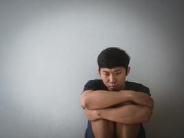 hombre asiático deprimido sentado en la pared foto