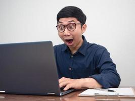 Asian businessman using laptop for working feels amazed photo