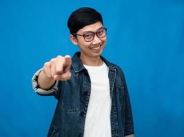 hombre asiático jeans camisa gesto señalar con el dedo a usted fondo azul foto