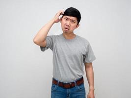 Asian man grey shirt stand scratch his head feels confused at face isolated photo