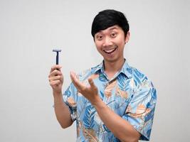 Asian man blue shirt cheerful smile show shaving in his hand isolated photo