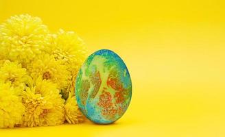 Yellow chrysanthemums with colored egg. Minimalism. Easter. Copy space photo