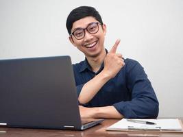 Positive businessman smile and point finger at copy space at working table photo