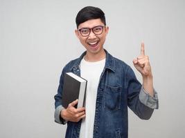 Positive man wear glasses jeans shirt cheerful gesture get idea hold the book in hand isolated photo