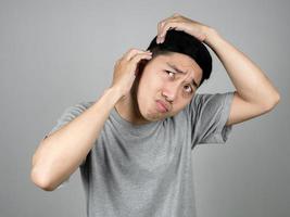 Asian man feels worried about grey hair on his head isolated photo
