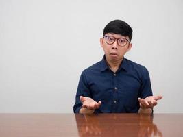 Asian businessman wear glasses sit at the table feels confused gesture i don't know photo