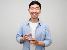 hombre asiático positivo camisa azul sostenga un vaso de agua sonrisa feliz aislado foto