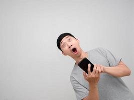 Man grey shirt feels shocked holding cellphone looking up isolated photo