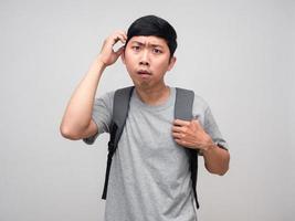 Asian man with backpack scratch head feels confused isolated photo