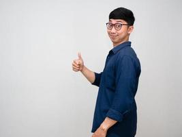 Positivel asian man wear glasses turn around to show thumb up isolated photo