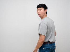 Asian young man grey shirt feels amazed turn back to looking isolated photo