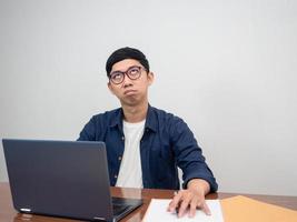 Asian man wear glasses sitting at working table feels bored about work photo