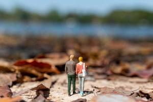 gente en miniatura, jóvenes amantes tomados de la mano mientras pasean por un parque en otoño foto