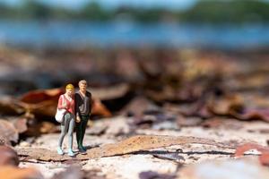 gente en miniatura, jóvenes amantes tomados de la mano mientras pasean por un parque en otoño foto
