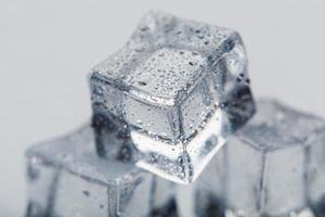 Ice cube with water drops close - up in macro on a white background. Refreshing ice. Isolate photo