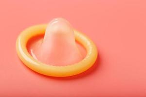 Condom without packaging on a pink background, close-up, top view. Rubber product for safe sex. photo