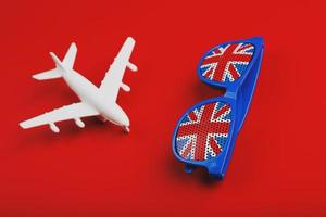 White airplane and sunglasses with the flag of the United Kingdom on a red background. Travel to England. photo