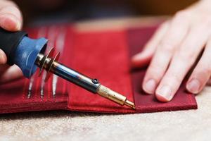 A leather craftsman works with leather. Sews leather goods. Making things handmade. photo