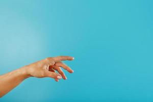 A woman's hand requiring support and help stretches on a blue background. photo