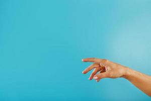 A woman's hand requiring support and help stretches on a blue background. photo