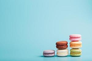 Multicolored French macaroni macaroni cookies are arranged in a pyramid on a blue background. photo