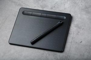 Graphic tablet with a stylus on a dark textural background, top view. Gadget for working as a designer, artist and photographer photo
