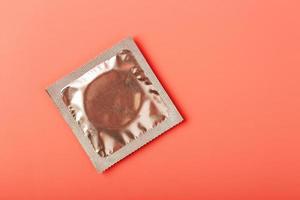 Packed condom on a pink background, close-up, top view. photo