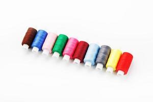 coloridos hilos de coser artesanales de algodón multicolores en una fila aislados en un fondo blanco. foto