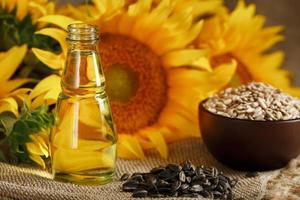 Sunflower oil with sunflower seeds and flowers on a wooden background. photo