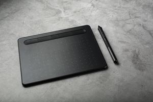tableta gráfica con un lápiz sobre un fondo textural oscuro, vista superior. gadget para trabajar como diseñador, artista y fotógrafo foto