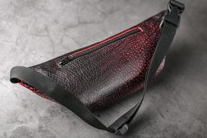 Bag on the belt of textured leather in Bordeaux colour , banana on a gray background.