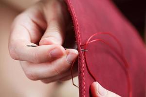 Conceptual profession of a Tanner. The woman's hands closed around the needle and thread. photo