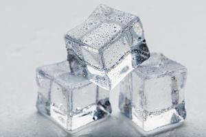 cubos de hielo en forma de pirámide con gotas de agua cerca - en macro sobre un fondo blanco. foto