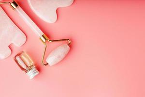 Gua sha massage tool made of natural pink Quartz-roller, jade stone and oil, on a pink background for face and body care. Part of traditional Chinese medicine photo