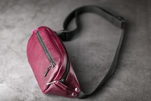 Waist bag made of dark red leather, banana on a gray background. photo
