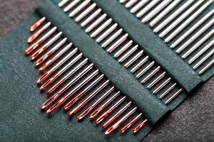 Sewing needles of different sizes in a set of red on a black background. photo