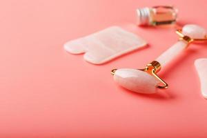 Gua sha massage tool made of natural pink Quartz-roller, jade stone and oil, on a pink background for face and body care. Part of traditional Chinese medicine photo