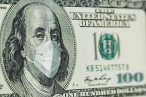 retrato de benjamin franklin billetes de 100 dólares con una máscara médica del coronavirus covid-19. foto