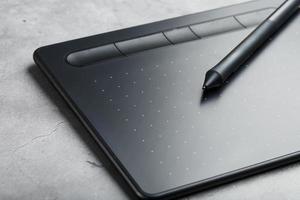 tableta gráfica con un bolígrafo sobre un fondo gris, obra de un diseñador, artista y fotógrafo. la vista desde arriba foto