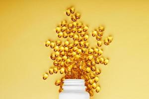 cápsulas doradas de aceite de pescado omega-3 vertidas de un frasco sobre un fondo amarillo foto