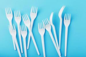 White plastic forks of disposable tableware on a blue background. photo