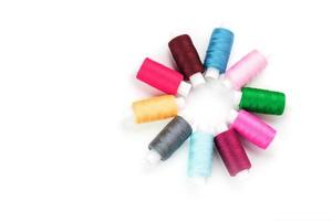 Sewing threads of different colors on reels on a white background in a circle. photo