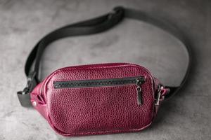 Waist bag made of dark red leather, banana on a gray background. photo