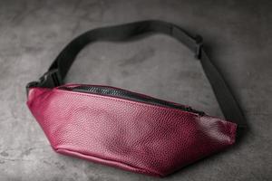 Waist bag made of dark red leather, banana on a gray background. photo