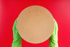 The parcel from the delivery service in the hands with green rubber gloves on a red background. photo