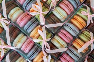 galletas de macarrones de diferentes colores en un paquete con lazo, muchas cajas con galletas en forma de textura. foto